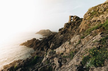 Alacakaranlıkta kayalıklarda duran yalnız balıkçı. Pointe du Grouin in in Bretagne.