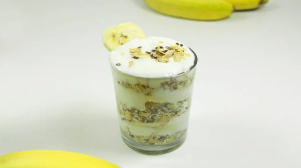 Greek Yogurt Banana Parfait topped with Banana Slices in a Glass on a White Background