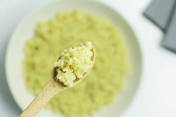 Bir kase pişmiş Quinoa beyaz bir tablo üzerinde bir tahta kaşık Quinoa pişmiş