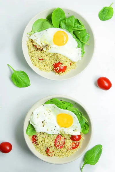 Ispanak, domates ve kızarmış yumurta ile lezzetli Breakfast Quinoa. Beyaz bir arka plan üzerinde sağlıklı gıda