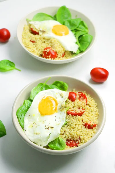 Ispanak, domates ve kızarmış yumurta ile lezzetli Breakfast Quinoa. Beyaz bir arka plan üzerinde sağlıklı gıda