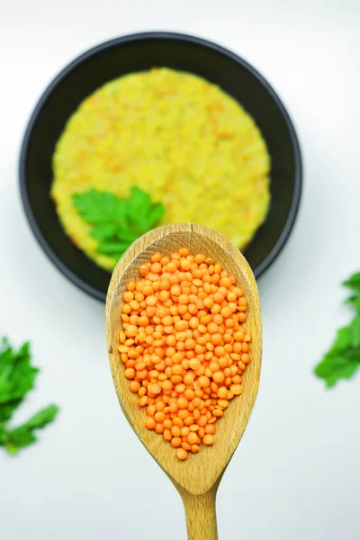 Beyaz bir tablo üzerinde siyah bir kasede maydanoz ile tepesinde sağlıklı mercimek püresi