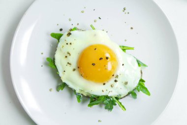 Ricotta, roka ve Fried fresnels sandviçle beyaz bir tabağa yumurta. Sağlıklı gıda