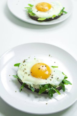 Ricotta, roka ve Fried fresnels sandviçle beyaz bir tabağa yumurta. Sağlıklı gıda