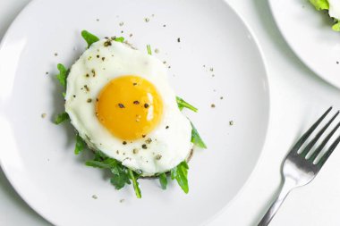 Ricotta, roka ve Fried fresnels sandviçle beyaz bir tabağa yumurta. Sağlıklı gıda