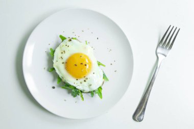 Ricotta, roka ve Fried fresnels sandviçle beyaz bir tabağa yumurta. Sağlıklı gıda