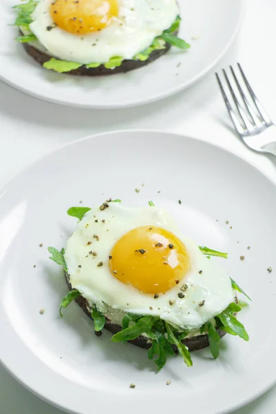Ricotta, roka ve Fried fresnels sandviçle beyaz bir tabağa yumurta. Sağlıklı gıda