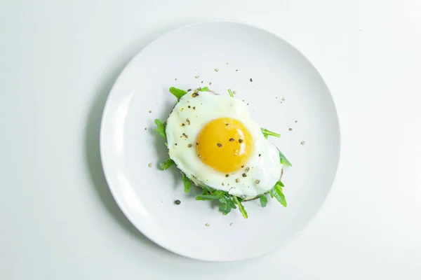 Ricotta, roka ve Fried fresnels sandviçle beyaz bir tabağa yumurta. Sağlıklı gıda