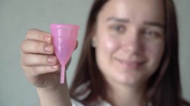 Yüzünün önünde yeniden kullanılabilir silikon adet fincan tutan genç bir kadın el yakın. Sıfır atık adet hijyen konsepti. Dönemler için ekolojik alternatif.
