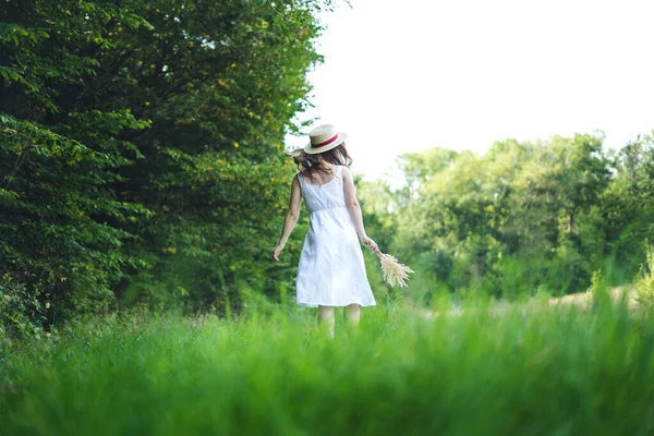 Młoda Kobieta Spacerująca Zielonym Polu Młoda Dziewczyna Białej Sukience Kapeluszu — Zdjęcie stockowe