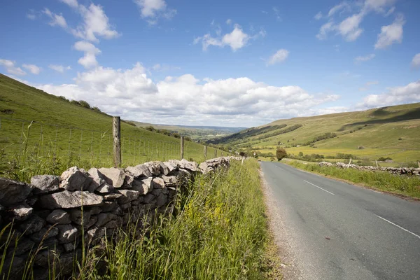 Route droite au-dessus du Yorkshire Dales avec mur de pierre traditionnel le long — Photo