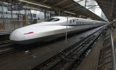 High-speed bullet train stopped at a modern station in an urban environment.