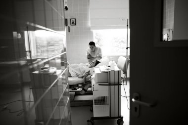 Kocası onun hamile eşi yatağın yanında duruyor ve annelik hospial elini tutar. Kadın bir mücâdele etti ve ona acıyor