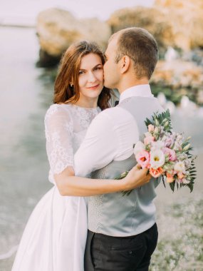 Yeni evliler, deniz arka plan güzel portresi. Gelin damat öpüşme.
