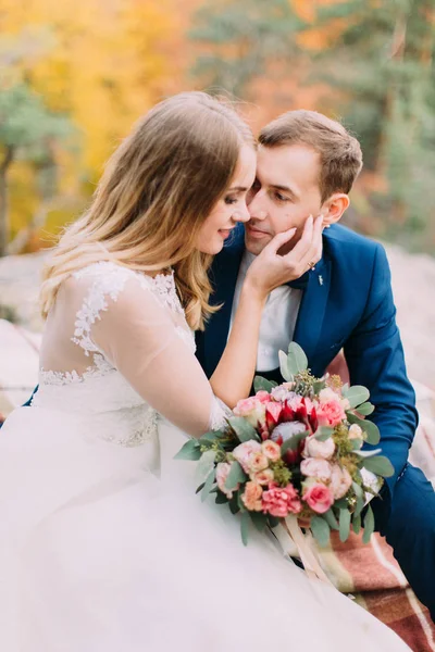 Detail pohledu nevěsty hladil po tváři ženicha zatímco sedí na skále. — Stock fotografie