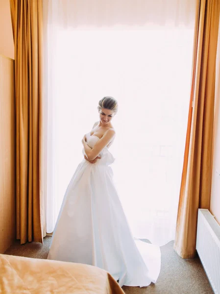 ウィンドウの前に立っている白い長いウェディング ドレスの花嫁の垂直方向のビュー. — ストック写真