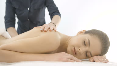 Rahat genç güzel kadın profesyonel sırt masajı beyaz arka plan üzerinde spa salonda alıyor demektir. 4 k görüntüleri.