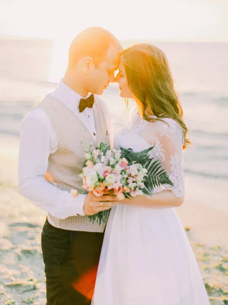 Het portret van de close-ondersteboven van de pasgetrouwden hand in hand op de achtergrond van de zonsondergang. — Stockfoto