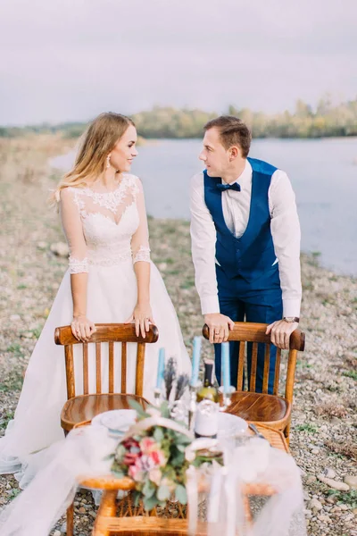 Deniz kenarı sandalyelere eğilerek mutlu yeni evli çiftin yakın çekim portre. — Stok fotoğraf