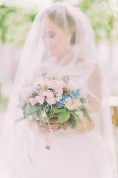 Vue rapprochée du bouquet de mariage sous le voile dans les mains de la mariée . — Photo