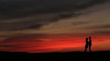 Siluet hafifçe üzerinde güzel kırmızı ve gri gökyüzü günbatımı sırasında öpüşme çekici çift.