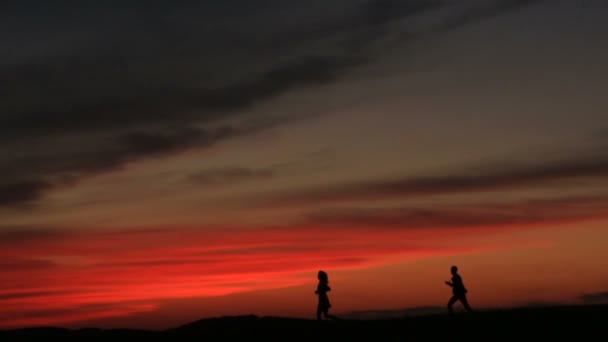 La silhouette dell'uomo che corre dietro è donna amorevole sopra il tramonto luminoso. La coppia felice si sta divertendo. Bella vista sulla natura . — Video Stock