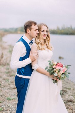 Damat gelini geri deniz manzarası eşliğinde sarılma varoluş portresi.