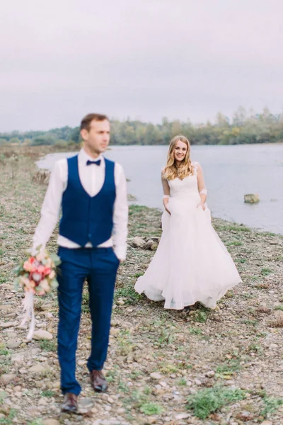 Bulanık damat önünde plaj boyunca neşeli yürüyüş gelin.