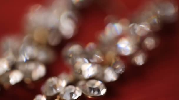 Close-up beeld van de diamanten halsketting tegen de rode achtergrond. Bewegende cameraweergave. — Stockvideo