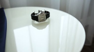 Şık gümüş handwatch kahverengi deri toka ve mavi kravat ile masaya yalan söylüyorsun. Erkek el aksesuar alıyor.