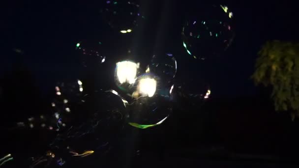Flying soap bubbles over the street lamp and city at night. — Stock Video
