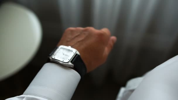 L'uomo elegante sta masticando tempo. Indossa il lussuoso orologio d'argento con fibbie in pelle marrone. Senza volto . — Video Stock