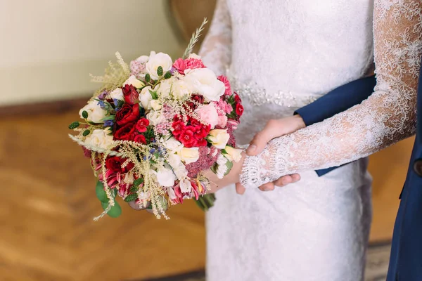 Vue rapprochée des mains de la mariée tenant le bouquet coloré de roses et différentes herbes . — Photo