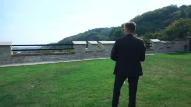 Yakışıklı şık damat düğün buket çiçek açan bahçede tutan güneş gözlüklü Steadycam görüntüleri.