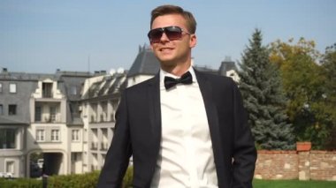 Güneş gözlüğü takıyor ve Bahçe yürüyüş yakışıklı şık giyimli damat portresi.