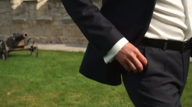 Siyah takım elbise ve gülümsemek güneş gözlüğü moda çekici damat Bahçe yürüyor. Hareketli kamera.