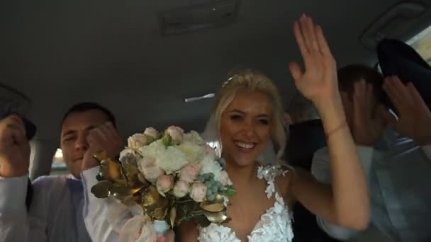 Attraktive junge Braut hat Spaß und lacht mit ihren Freunden während der Autofahrt. — Stockvideo