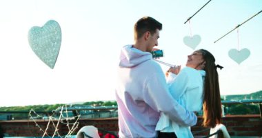 Gülüyor ve çatı katında selfies cep telefonu üzerinden alarak beyaz metal kalpleri ile dekore ederken mutlu güzel çift eğlenceli yaşıyorsanız. 4 k görüntüleri.