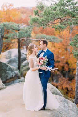 Romantik arka plan sararmış ormanın kayaya tutuyoruz sarılma yeni evliler bakış.