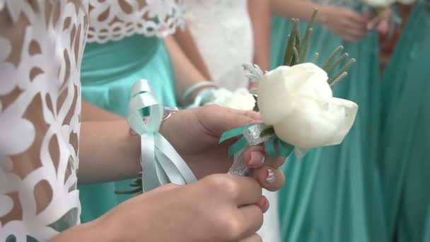 Vrouwelijke handen van bruidsmeisjes houden de corsages van Witte pioen omwikkeld met zilver lint. — Stockvideo