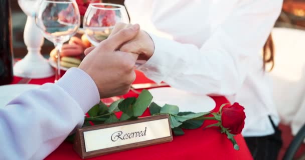 Romantic outdoor dinner of the couple holding hands. Table decorated with the plaque Reserved and red rose. No face. 4k footage. — Stock Video