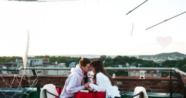 Elele ve usulca çatıda Tarih boyunca burun sürtme çekici mutlu genç çift metal kalpleri ile dekore edilmiş. Romantik bir atmosfer.