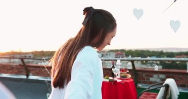 Neşeli çekici kız erkek arkadaşı çatıda romantik akşam yemeği için hizmet tablo yol açmaktadır. Romantik sürpriz.