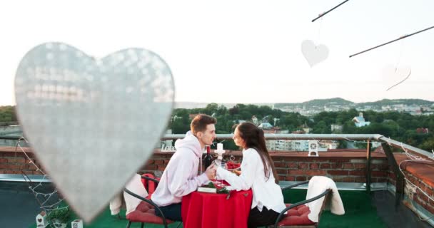 Una cita romántica en el tejado. Feliz hermosa pareja amorosa está cogida de la mano y tiernamente besándose. Imágenes de 4k . — Vídeo de stock