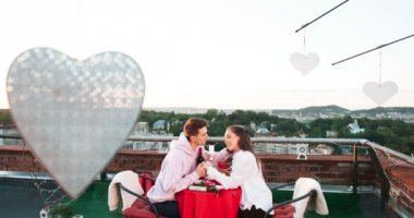 Romantik tarih çatıda. Duyarlı çift şefkatle elele geziyor. Adam sevgilisine yanağını okşayarak ve onu kafasından öpüşme.