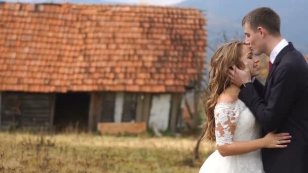 Wrażliwe portret newlywed para zakochana w jesień wsi w górach. Pan młody jest czule całuje młodej w głowie. — Wideo stockowe