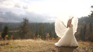 Etkin muhteşem gelin moda uzun elbiseli dağlarda altın ormanda onu peçe ile oynuyor.