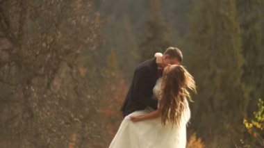 Aşık çifti düğün sonbahar dağlarda günbatımı sırasında dans ederken eğleniyor. Duygusal portre.