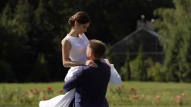 Yakışıklı damat yuvarlak kollarında onun sevimli gülümseyen esmer gelin Bahçe dönüyor.