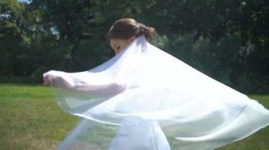 Mutlu bir şekilde yuvarlak iplik ve onu peçe ile oynarken çekici mutlu esmer gelin portresi.